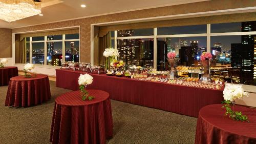 a restaurant with red tables and a view of the city at RIHGA Royal Hotel Osaka, Vignette Collection by IHG in Osaka