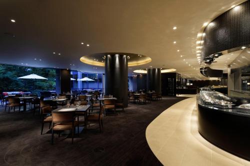 a restaurant with tables and chairs and a bar at RIHGA Royal Hotel Osaka, Vignette Collection by IHG in Osaka