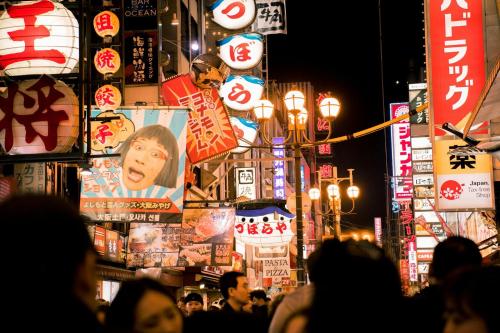 a crowd of people walking down a city street at night at RIHGA Royal Hotel Osaka, Vignette Collection by IHG in Osaka