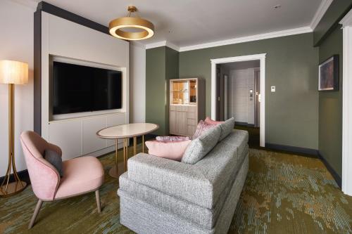 a living room with a couch and two chairs and a tv at RIHGA Royal Hotel Osaka, Vignette Collection by IHG in Osaka