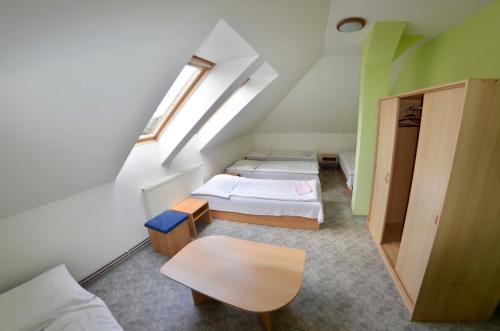 a attic room with three beds and a table at Penzion Poodří in Suchdol nad Odrou