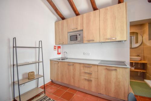 a kitchen with wooden cabinets and a microwave at Penedo Escape Nature in Colares