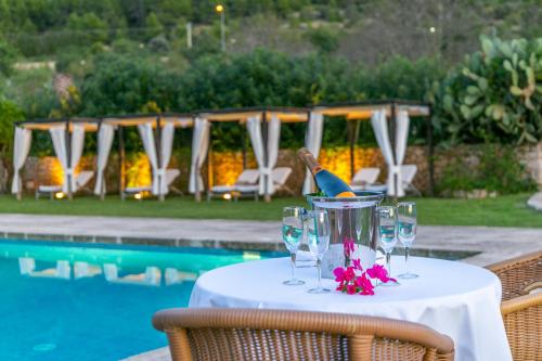 a table with wine glasses next to a pool at Historical house Mallorca pool wifi airconheat in Andratx