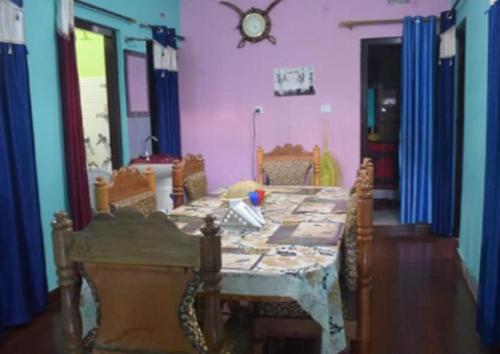 a room with a table with chairs and a clock on the wall at StayApart Mount Kailash Guest House in Munsyari