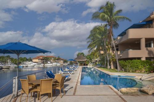 a pool at the resort with chairs and an umbrella at Portobello Gran Marina in Puerto Aventuras
