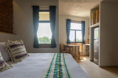 a bedroom with a bed and a table and windows at Aymara Punta Zicatela in Brisas de Zicatela