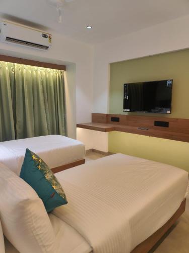a hotel room with two beds and a flat screen tv at Hotel Vaishnavi Heights, Solapur in Bāle