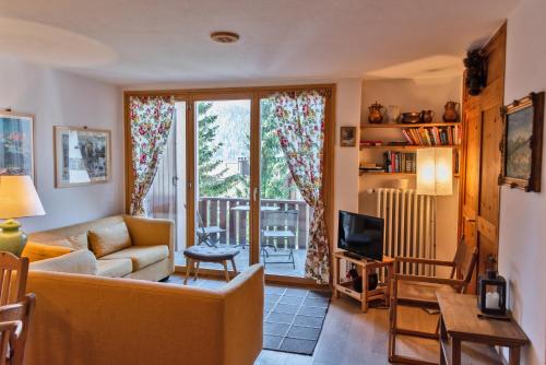 a living room with a couch and a tv at Chesa Alvra - Celerina in Celerina