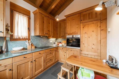 a kitchen with wooden cabinets and a wooden table at Chesa La Buot - Silvaplana in Silvaplana