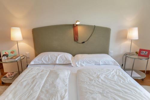 a bedroom with a white bed with a green headboard at Chesa Viroula - Zuoz in Zuoz