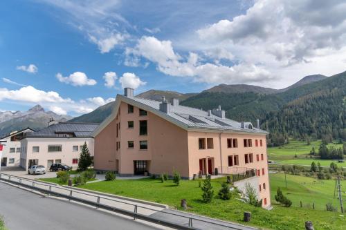 a house on the side of a road with mountains in the background at Chesa Viroula - Zuoz in Zuoz