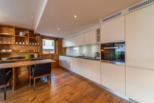 a kitchen with white cabinets and a wooden table at Chesa Flugi - Silvaplana in Silvaplana