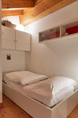 a bed in a room with white walls and wooden ceilings at Chesa Pedra - Celerina in Celerina