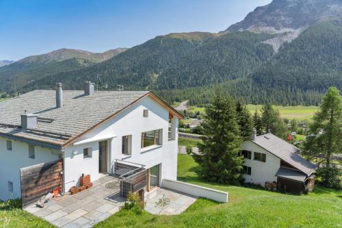 a white house with mountains in the background at Chesa Pino - Madulain in Madulain