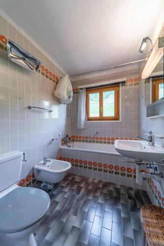 a bathroom with two sinks and a tub and a toilet at Chesa Gravulaina - Madulain in Madulain
