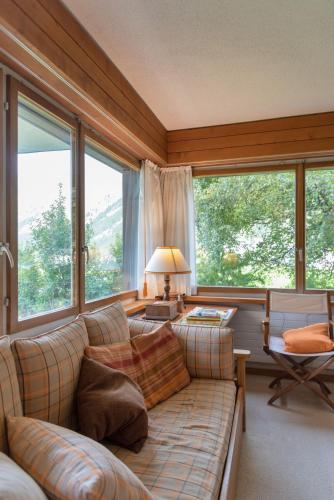 a living room with a couch and large windows at Chesa Muot Marias - Sils in Sils Maria