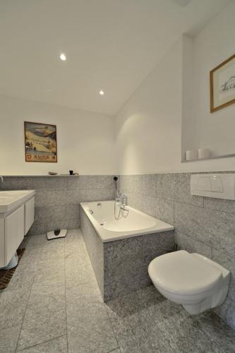 a bathroom with a toilet and a tub and a sink at Chesa Ladina - Zuoz in Zuoz