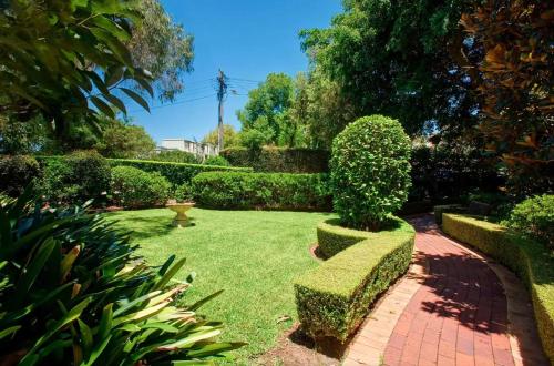 a garden with trimmed hedges and a brick walkway at Paddington chic at Five Ways in Sydney