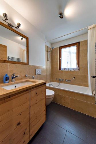a bathroom with a sink and a tub and a toilet at Engadina Chesa Gluna - Madulain in Madulain