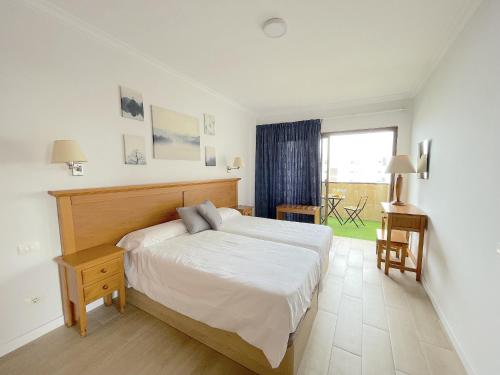 a bedroom with a bed and a desk and a window at Agaete Park 609 by Villas Rivero in Playa del Ingles