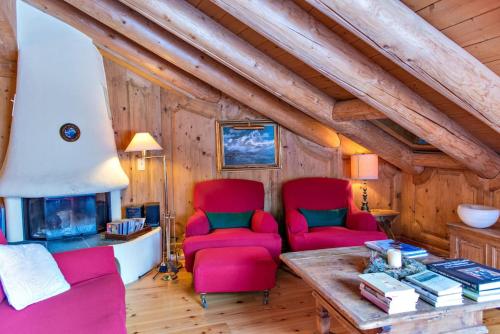 a living room with two red chairs and a fireplace at Chesa Romana - Silvaplana in Silvaplana