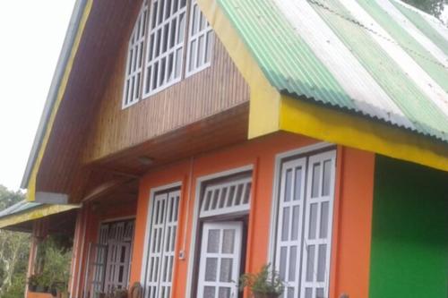 a colorful house with white windows and a green roof at Temi Sarika Homestay in Damthang