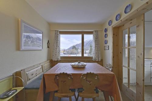 una sala da pranzo con tavolo, sedie e una finestra di Chesa Charots - Celerina a Celerina
