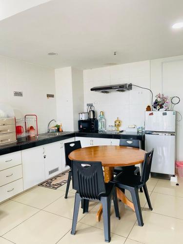 a kitchen with a wooden table and black chairs at EM Suite Homestay in Kota Bharu