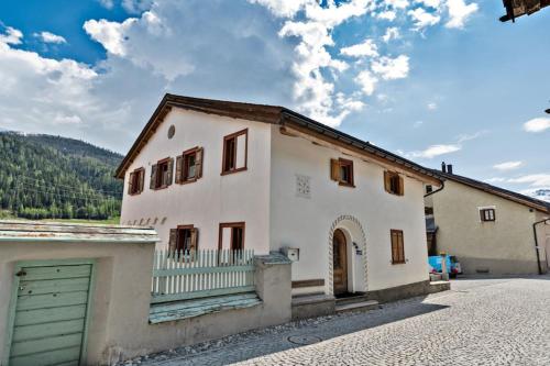 une maison blanche avec un portail et un garage dans l'établissement Chesa Violetta - S-chanf, à S-chanf