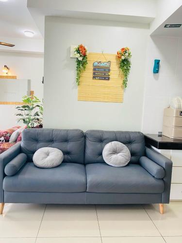 a blue couch with two pillows in a living room at EM Suite Homestay in Kota Bharu