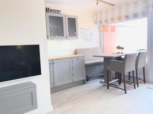 a living room with a table and a tv at STRANDIDYLL, 4 - Typ A4S in Grömitz