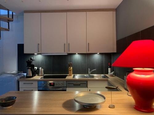 una cocina con armarios blancos y una lámpara roja en una mesa en Mini-Ferienhaus Petersberg, en Eckernförde