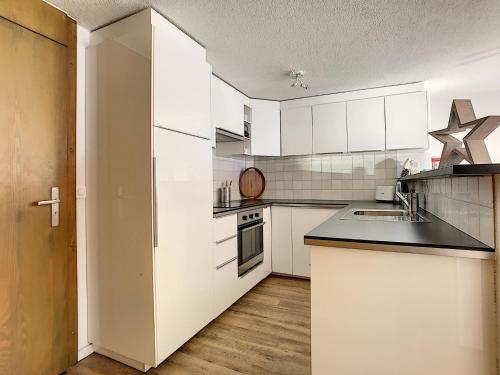 eine Küche mit weißen Schränken und einer schwarzen Arbeitsplatte in der Unterkunft Séracs 23 in Verbier