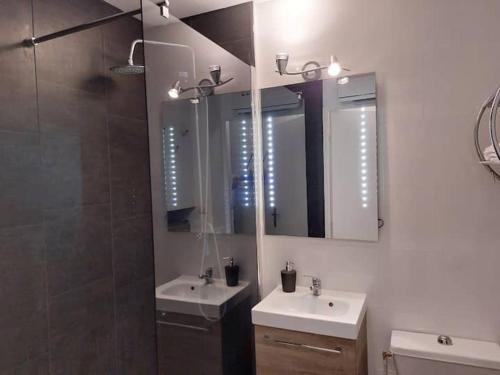 a bathroom with two sinks and a mirror at Le Petit Cabourg plage vue mer in Cabourg