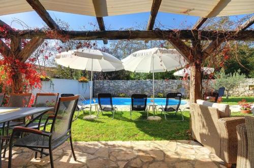 a patio with chairs and umbrellas and a pool at Villa Katherine with Pool and Game Room in Žminj