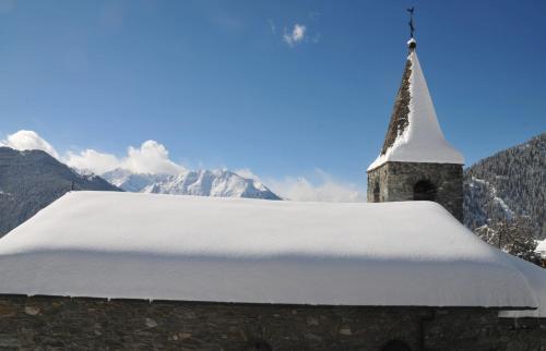 a church with a snow covered roof with mountains in the background at Laiterie 1 in Verbier