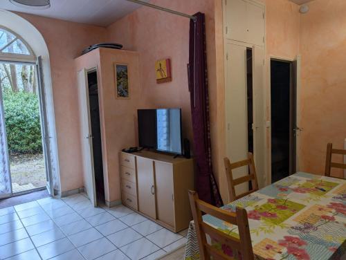 una sala da pranzo con tavolo e TV su un armadio di Appartement de plain pied , jardin et grande terrasse a Ussat