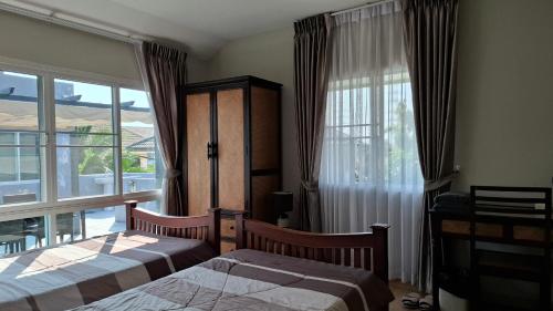 a bedroom with two beds and a large window at A,B house Chiangmai in Chiang Mai