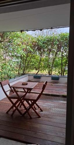 une table en bois et une chaise sur une terrasse dans l'établissement Cosi, à Gex