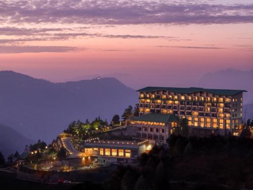 a hotel at night with mountains in the background at dusitD2 Fagu, Shimla in Shimla