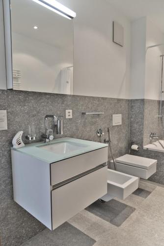 a white bathroom with a sink and a toilet at Chesa Chalavus - St. Moritz in St. Moritz