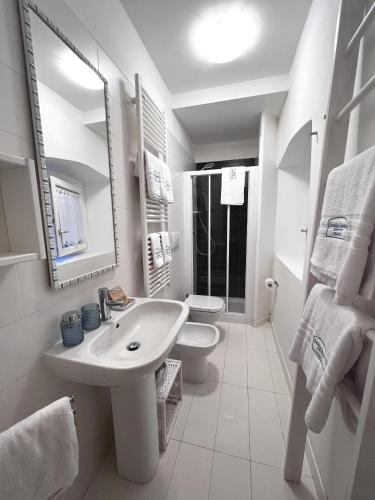 a white bathroom with a sink and a toilet at Scala Santa Apartment in Trieste