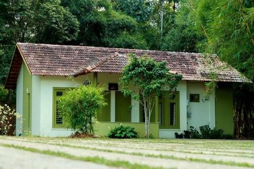 una piccola casa verde con tetto marrone di Ayurnest Pool Resort Wayanad a Batheri