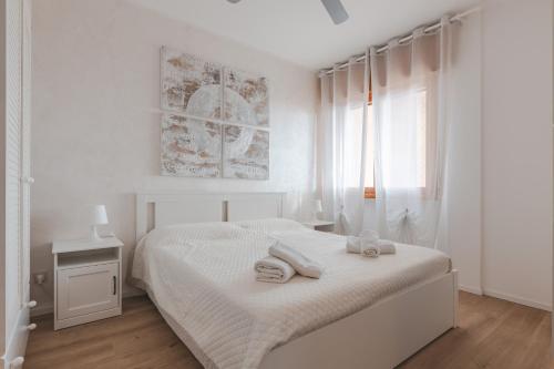 a white bedroom with a white bed and a window at ElTufeto Apartment - Parking and Terrace in Grado-Pineta