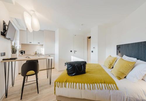a bedroom with a bed and a desk with a bag on it at Appart Hotel Neostelia in Annecy