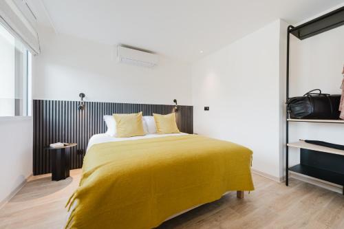a bedroom with a bed with a yellow blanket at Appart Hotel Neostelia in Annecy
