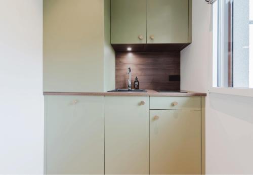 a kitchen with white cabinets and a sink at Appart Hotel Neostelia in Annecy