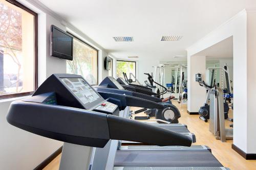 a gym with several treadmills and a row of exercise bikes at Novotel Bahrain Al Dana Resort in Manama
