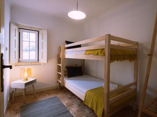 een slaapkamer met twee stapelbedden en een raam bij Casa Porta da Vila in Óbidos