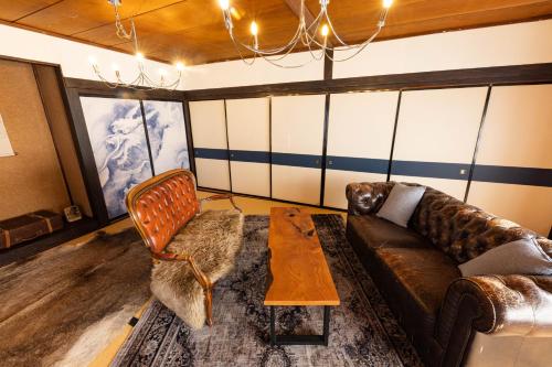 a living room with a leather couch and a table at 小グループ専門貸切一軒家 パーティーOK観光スポット徒歩圏内 小諸駅歩2分揚羽屋 Specializing in small groups, Party OK, Walking to tourist spots, Vacation Rental House 2 min from Komoro sta in Komoro